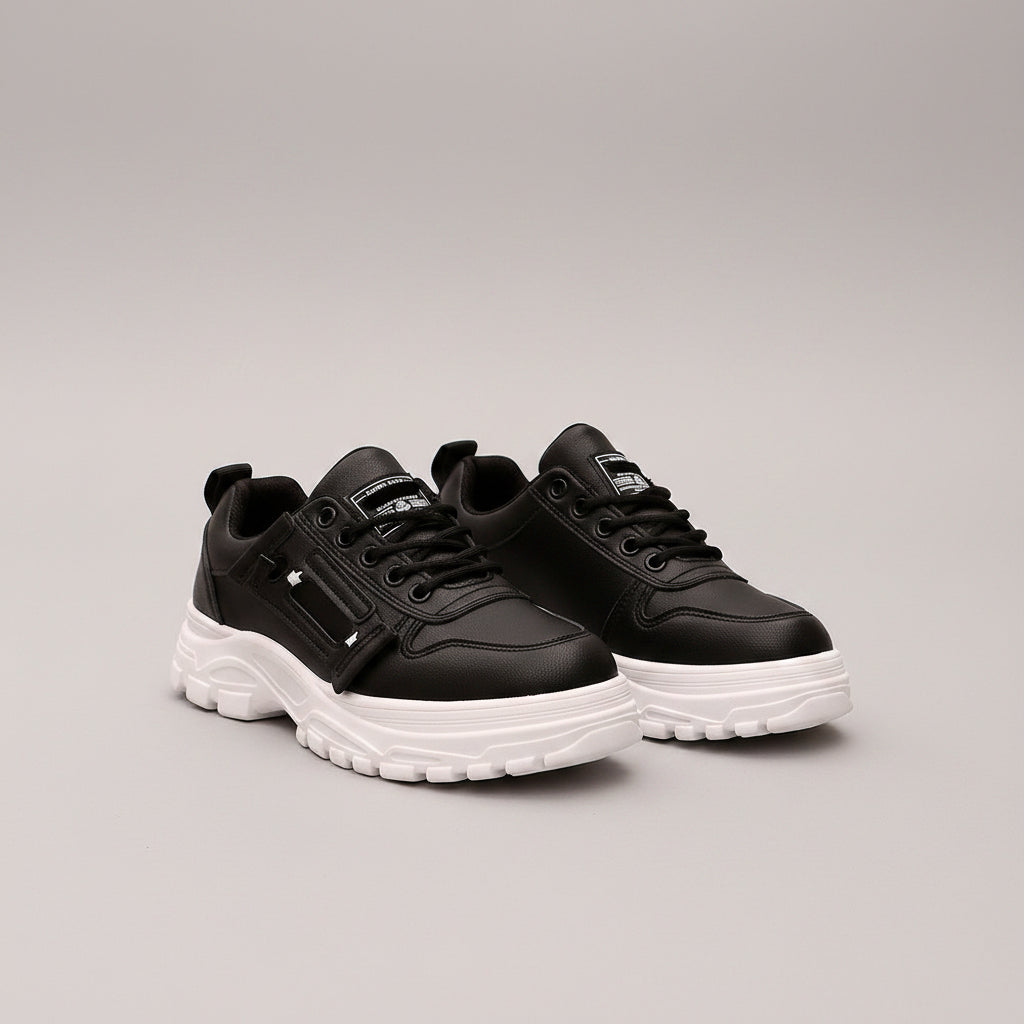 Black sneakers with white soles worn on a street.