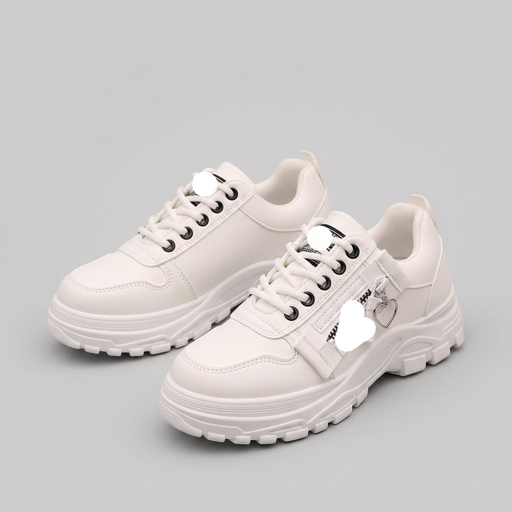 White sneakers with a brand label held by a person on a dark pavement background