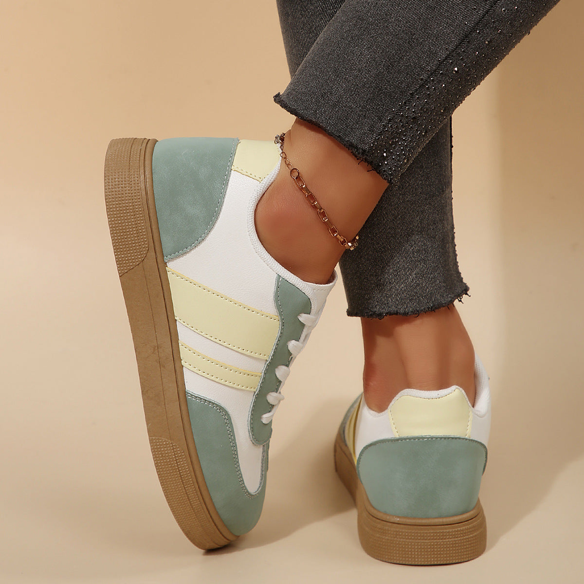 Multicolored sneakers worn with dark jeans on a beige background