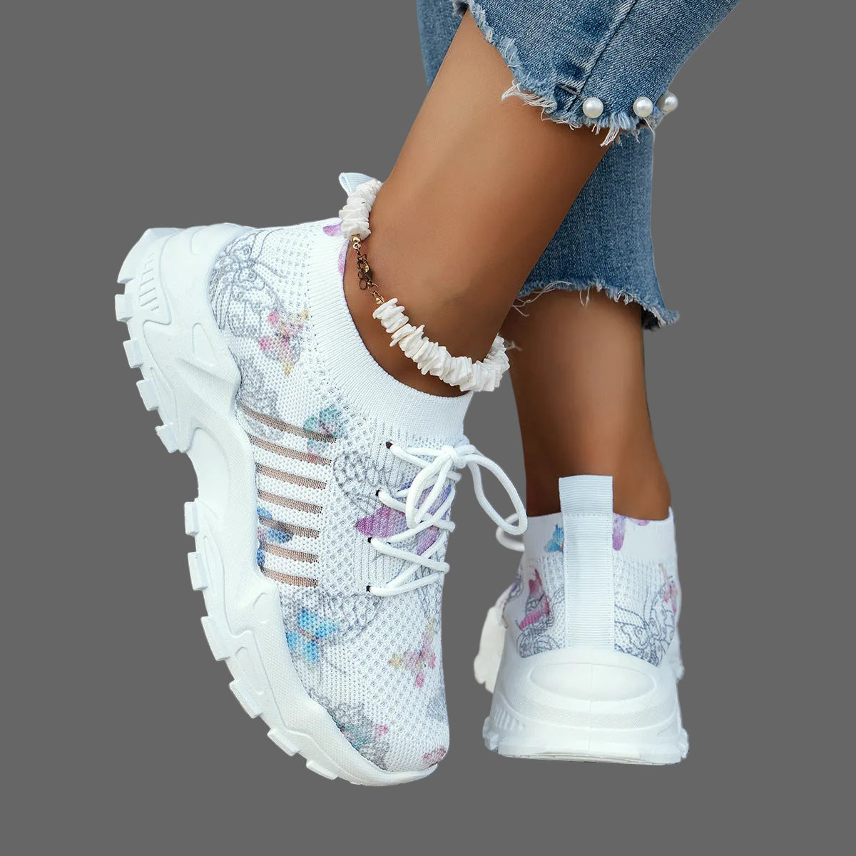 White sneakers with floral patterns worn by a person on a textured surface.